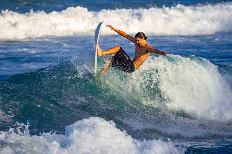 Surfer performing a trick on a wave in the ocean with sun zapper surf sunscreen